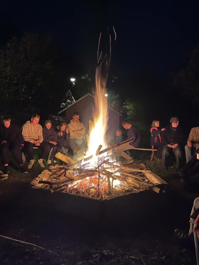 Am Lagerfeuer sitzen die Geschwister zusammen.